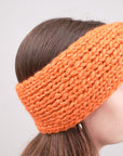 Alpaka-Stirnband Vero in Orange an einer Frau – seitliche Trageansicht mit sichtbarer Strickstruktur.