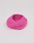 Gestricktes Stirnband in Pink von Manuela Bedford – aufgestellt mit gedrehter Vorderseite.