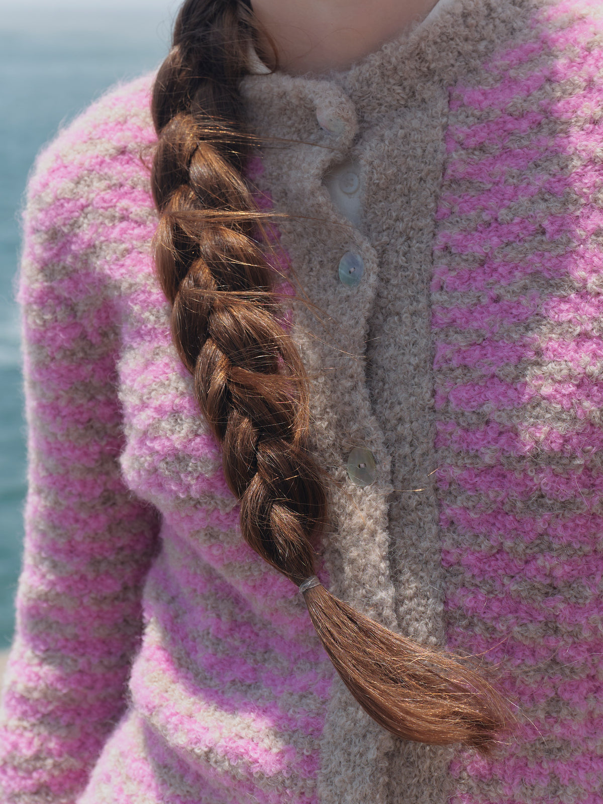 Detail der rosa-beigen Bouclé-Strickjacke Cruz: strukturierter Strick, beiger Stehkragen und helle Knöpfe.