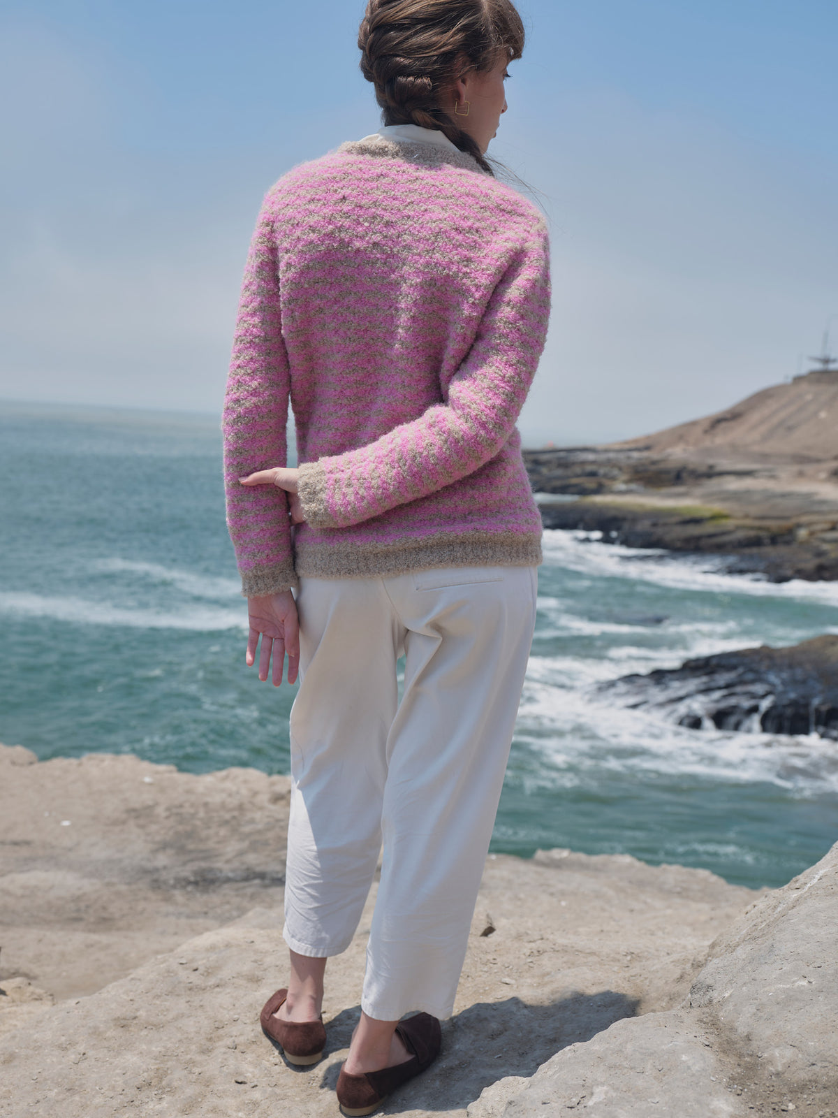 Rückansicht der Alpaka-Bouclé-Strickjacke Cruz in Rosa und Beige mit Streifenmuster und beigem Saum.