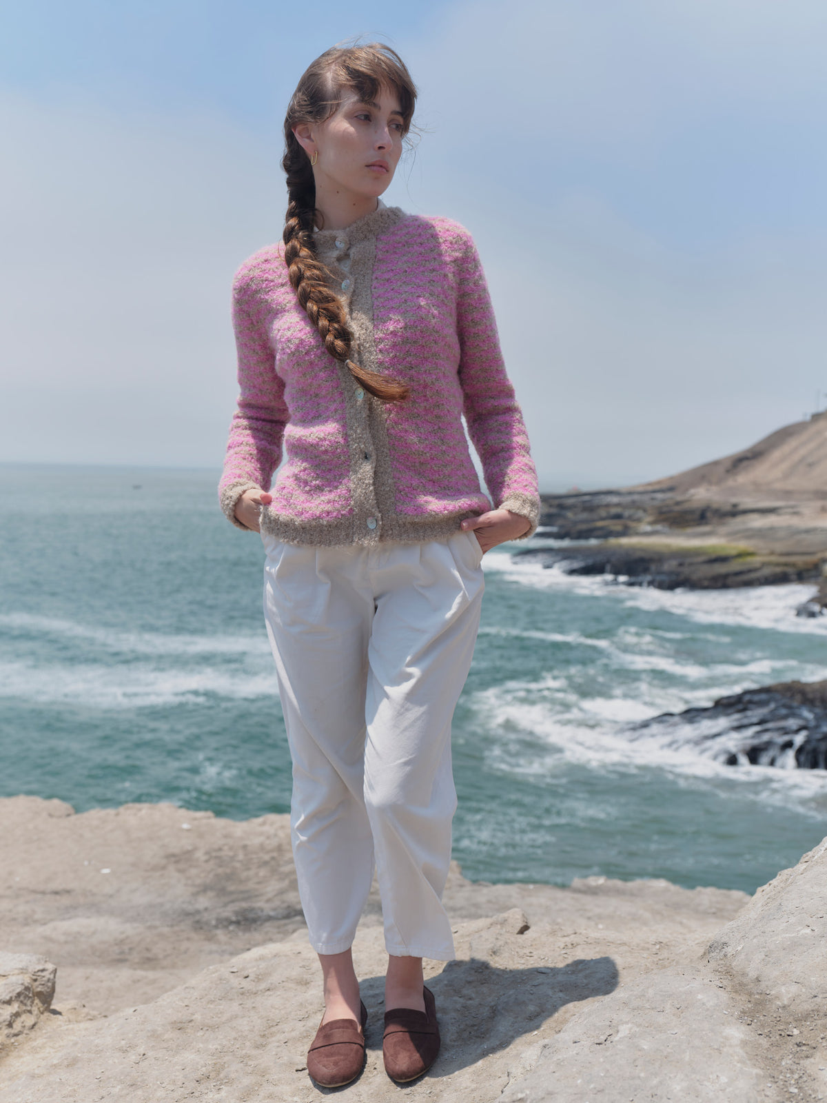 Alpaka-Bouclé-Strickjacke Cruz in Rosa und Beige von Manuela Bedford, Vorderansicht am Model mit weißer Hose.