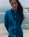 Türkise Bouclé-Strickjacke Cruz am Model, Vorderansicht mit Stehkragen und durchgehender heller Knopfleiste.