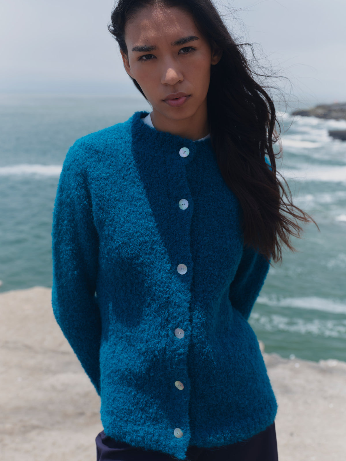 Türkise Bouclé-Strickjacke Cruz am Model, Vorderansicht mit Stehkragen und durchgehender heller Knopfleiste.