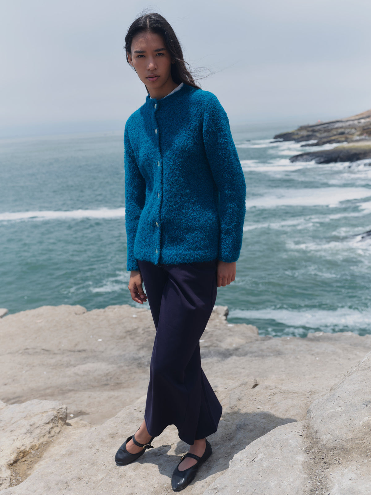Alpaka-Bouclé-Strickjacke Cruz in Türkis von Manuela Bedford, Vorderansicht am Model mit dunklem Rock.