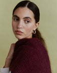 Alpaka-Oversize-Schal Gabriela in Berry, um die Schultern gelegt – Nahaufnahme von Schulter und Strickstruktur.
