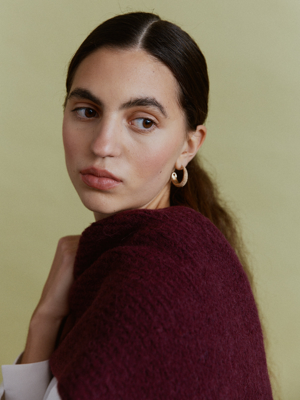 Alpaka-Oversize-Schal Gabriela in Berry, um die Schultern gelegt – Nahaufnahme von Schulter und Strickstruktur.