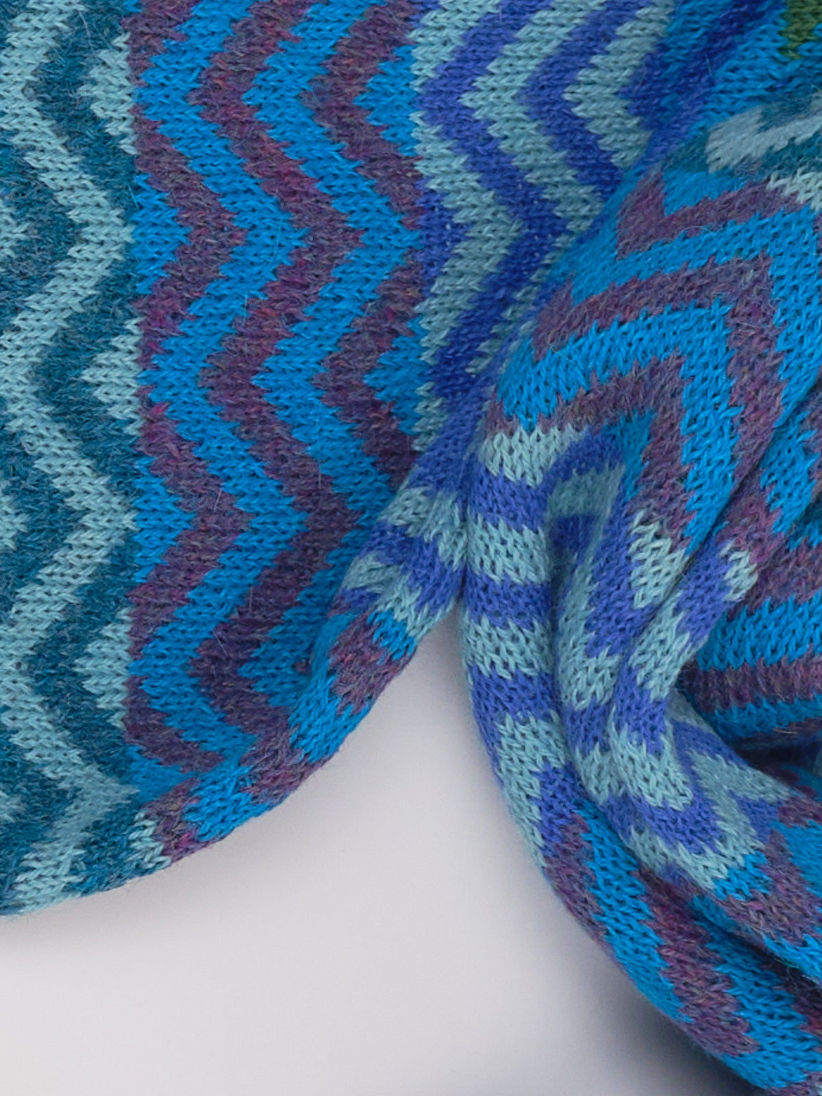 Detail des Alpaka-Schals ZigZag in Türkis mit Zickzackmuster in Blau-, Türkis- und Violetttönen.