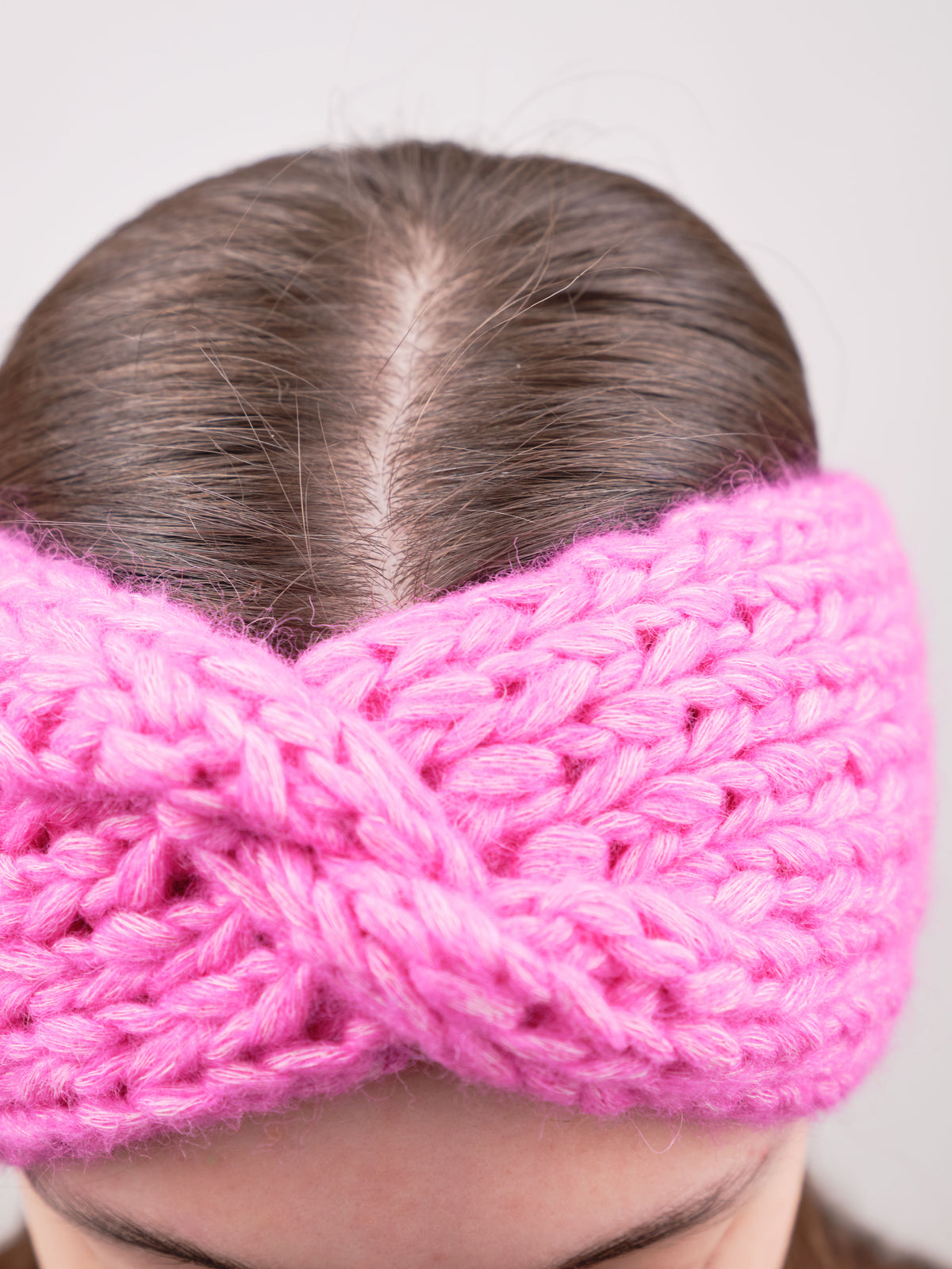 Alpaka-Stirnband Vero in Fuchsia an einer Frau – Frontansicht der gedrehten Vorderseite.