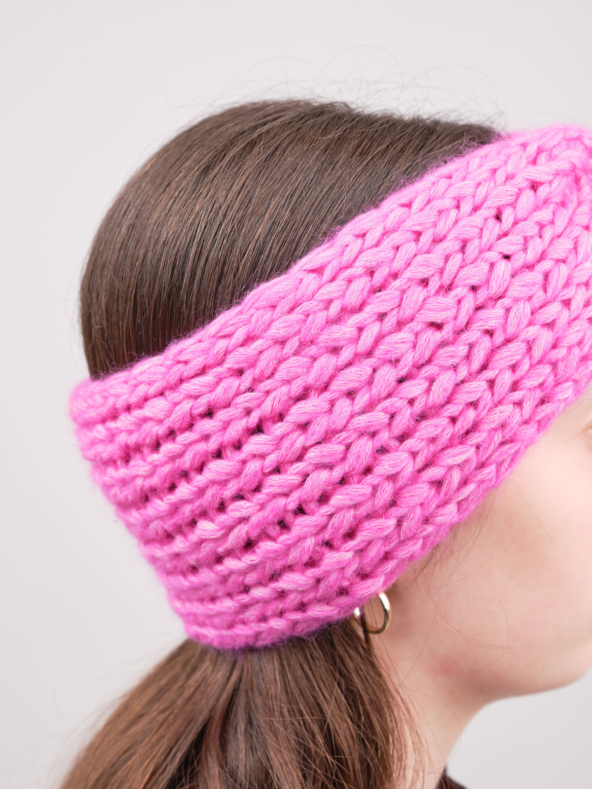 Alpaka-Stirnband Vero in Fuchsia an einer Frau – seitliche Trageansicht mit sichtbarer Strickstruktur.