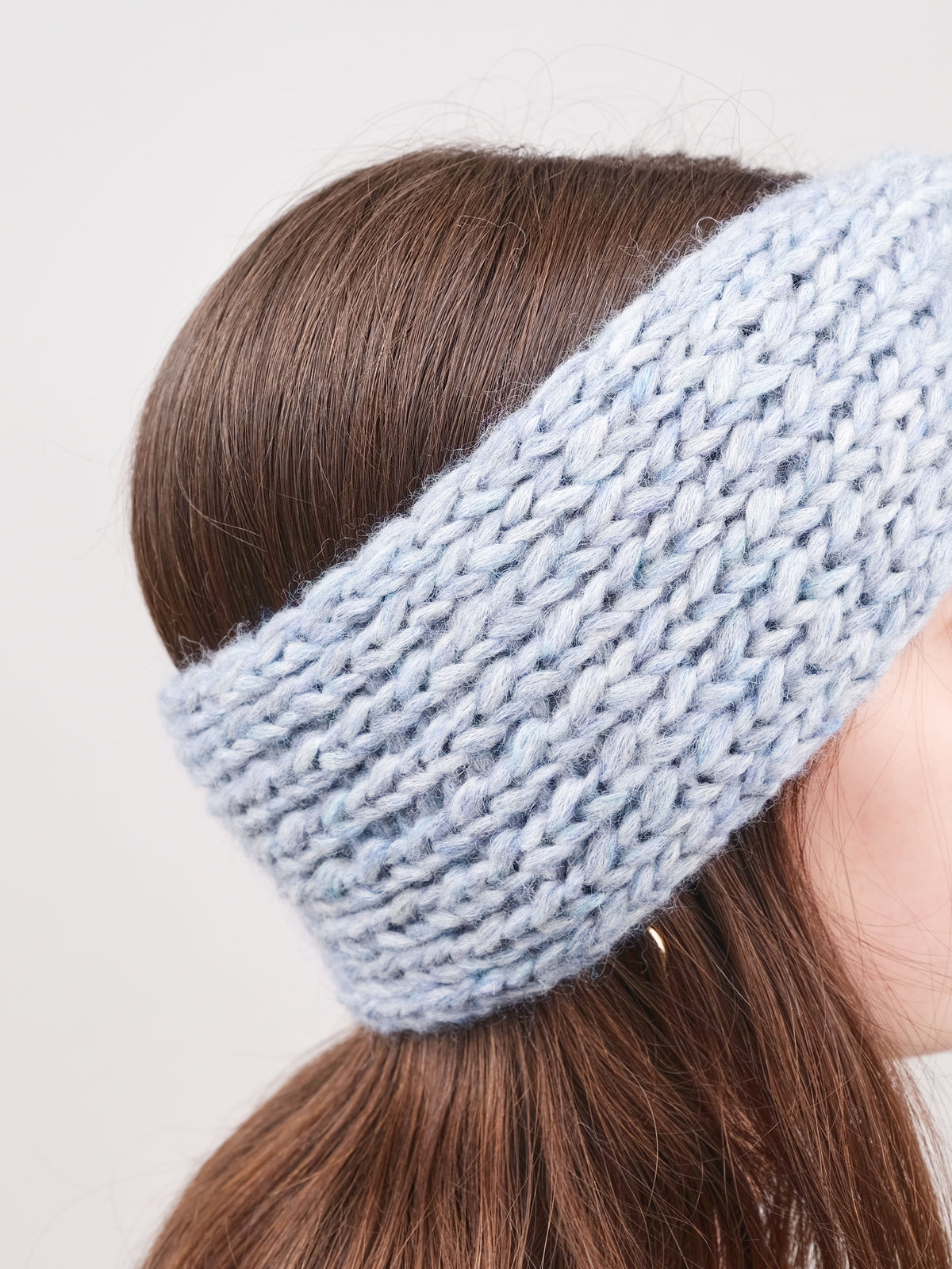Alpaka-Stirnband Vero in Grau an einer Frau – seitliche Trageansicht mit sichtbarer Strickstruktur.