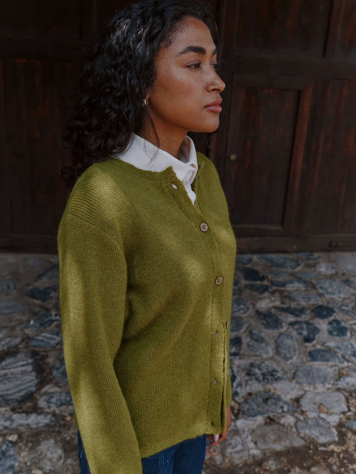 Seitenansicht der Rundhals-Strickjacke Klassik aus Alpaka in Grün von Manuela Bedford.