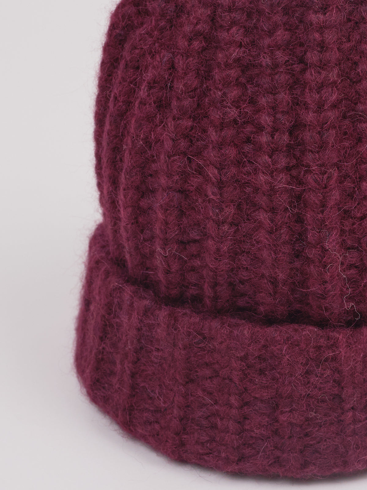 Baby-Alpaka-Mütze in Berry von Manuela Bedford – Nahaufnahme der Strickstruktur und des umgeschlagenen Bündchens.