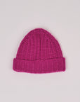 Baby-Alpaka-Mütze in Fuchsia von Manuela Bedford – flach ausgelegt mit umgeschlagenem Bündchen.