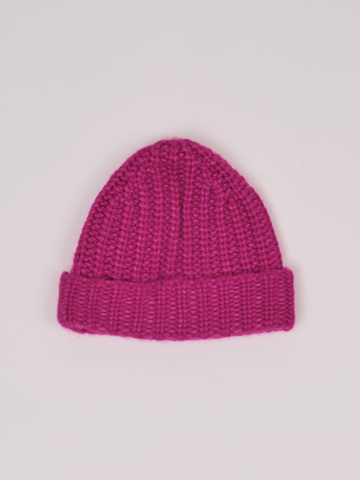 Baby-Alpaka-Mütze in Fuchsia von Manuela Bedford – flach ausgelegt mit umgeschlagenem Bündchen.