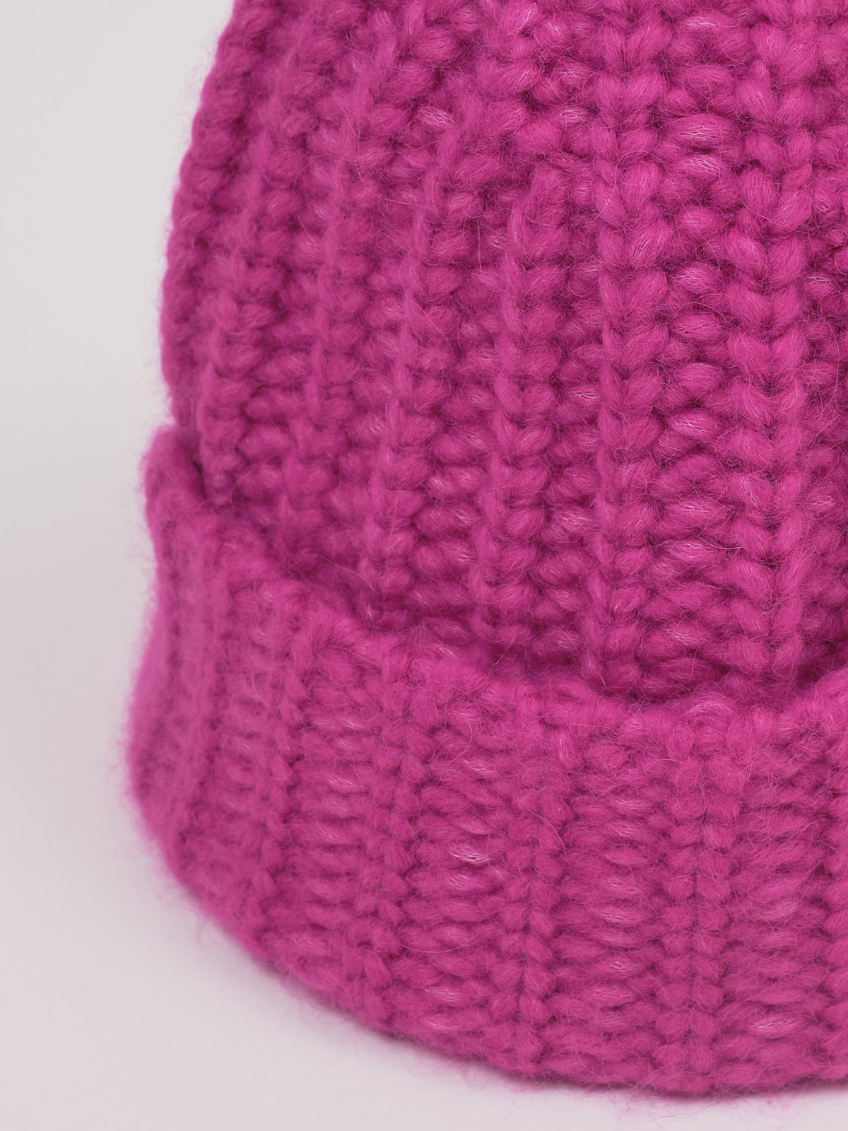 Baby-Alpaka-Mütze in Fuchsia von Manuela Bedford – Nahaufnahme der Strickstruktur und des umgeschlagenen Bündchens.