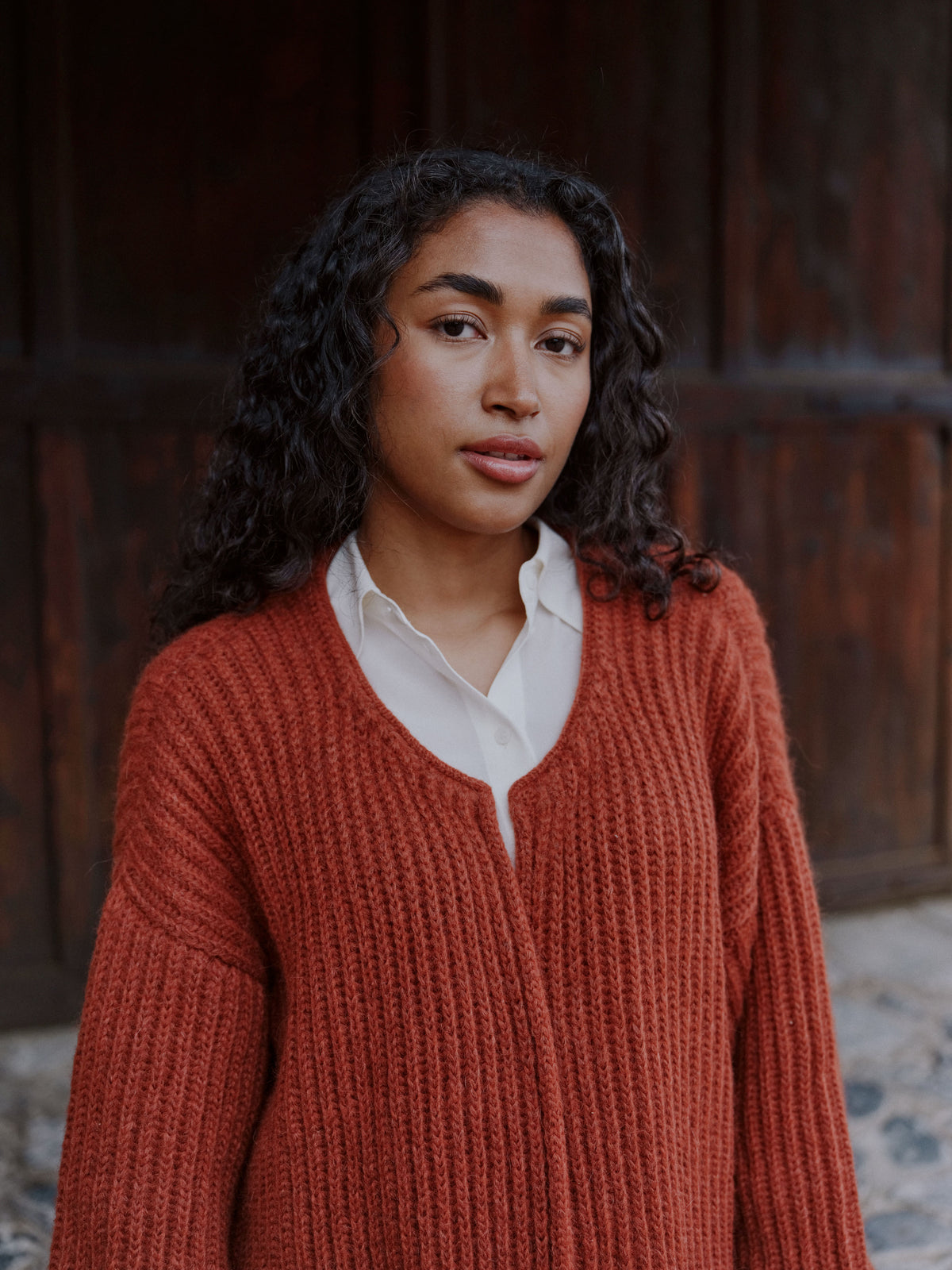 Porträt mit der offenen Strickjacke Tinki aus Baby Alpaka in Braun von Manuela Bedford.