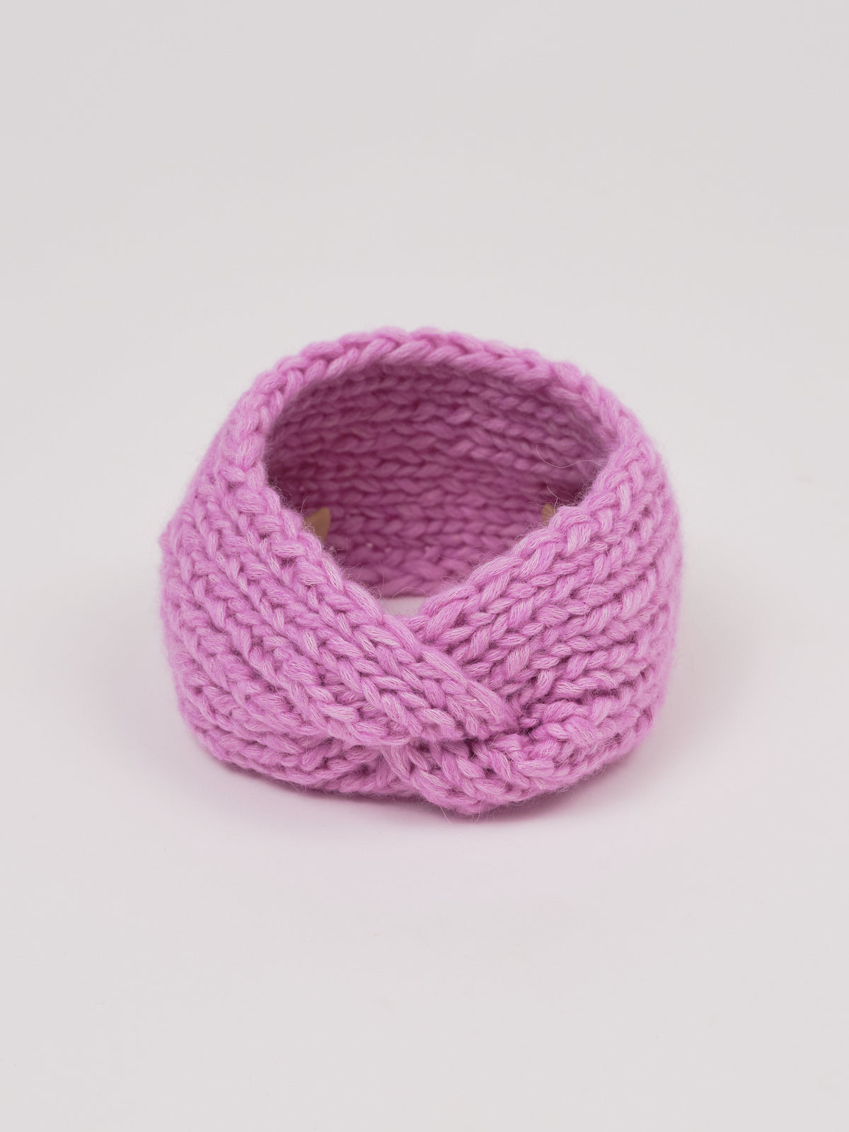 Gestricktes Stirnband in Flieder von Manuela Bedford – aufgestellt mit gedrehter Vorderseite.