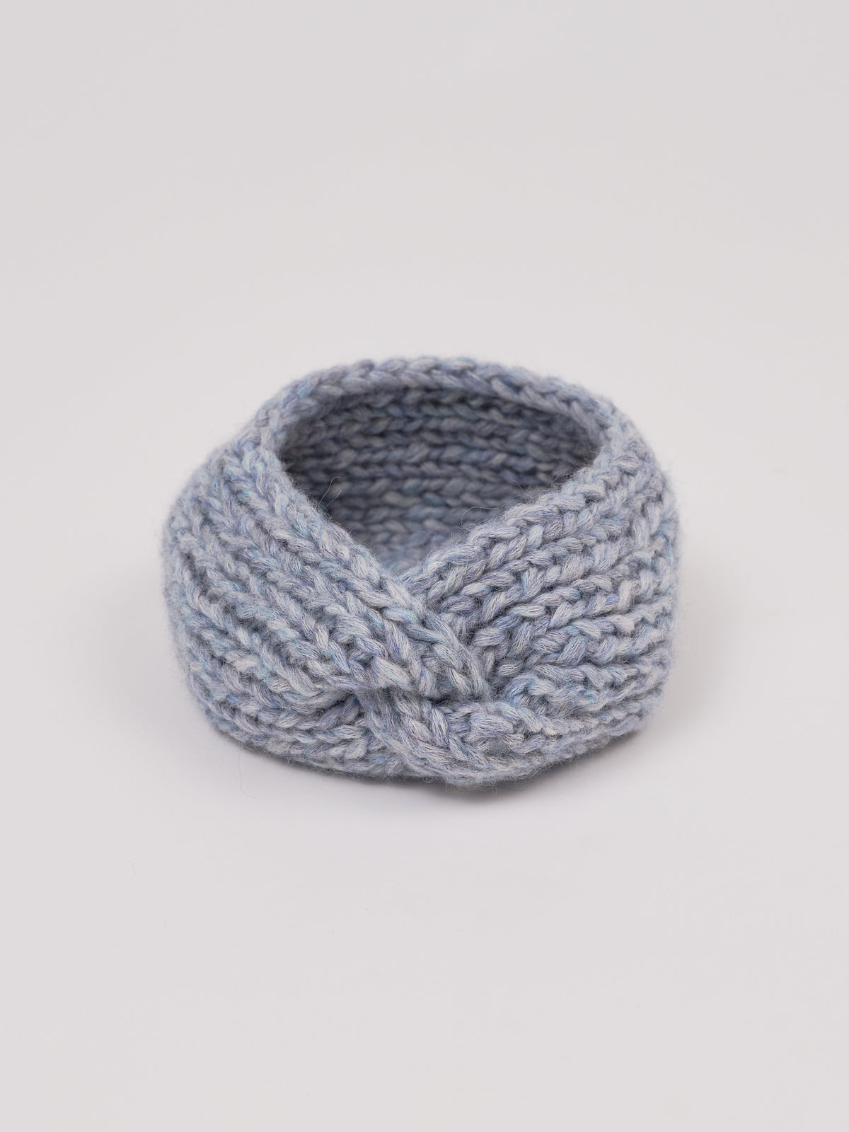 Gestricktes Stirnband in Grau von Manuela Bedford – aufgestellt mit gedrehter Vorderseite.
